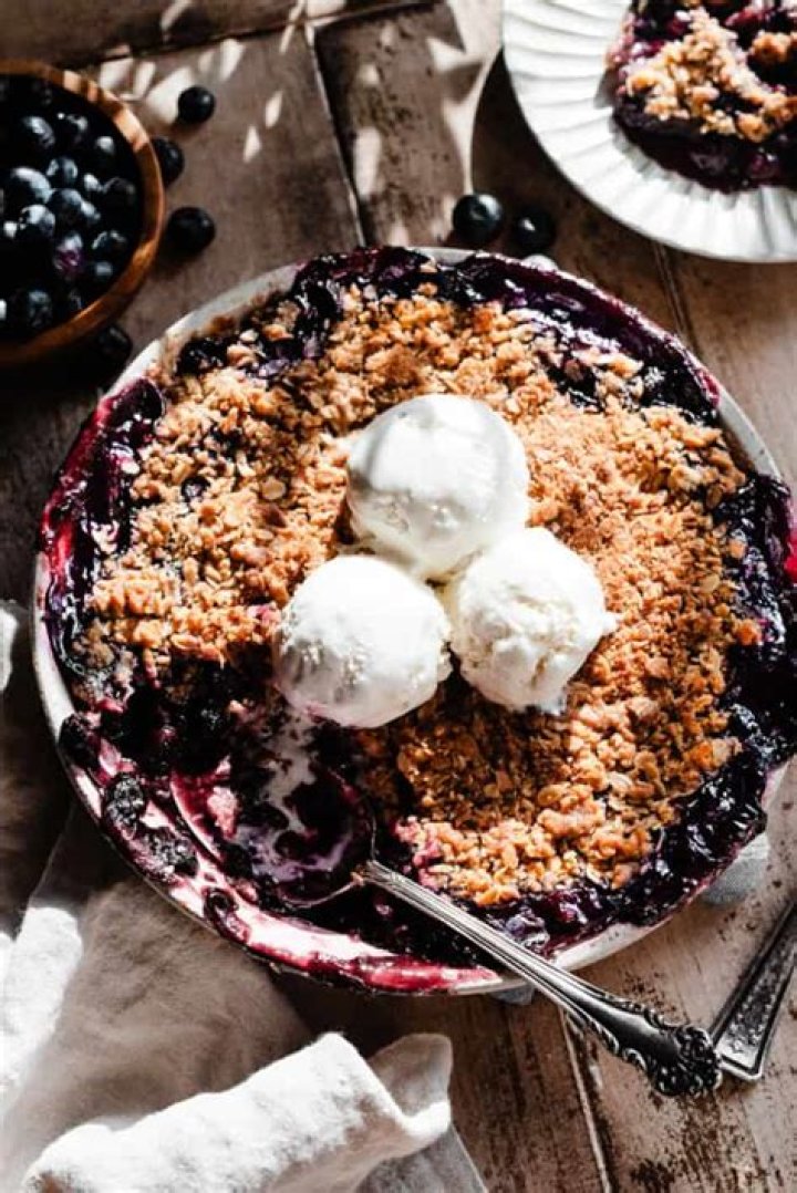 Blueberry Crisp topped with ice cream in a white bowl.