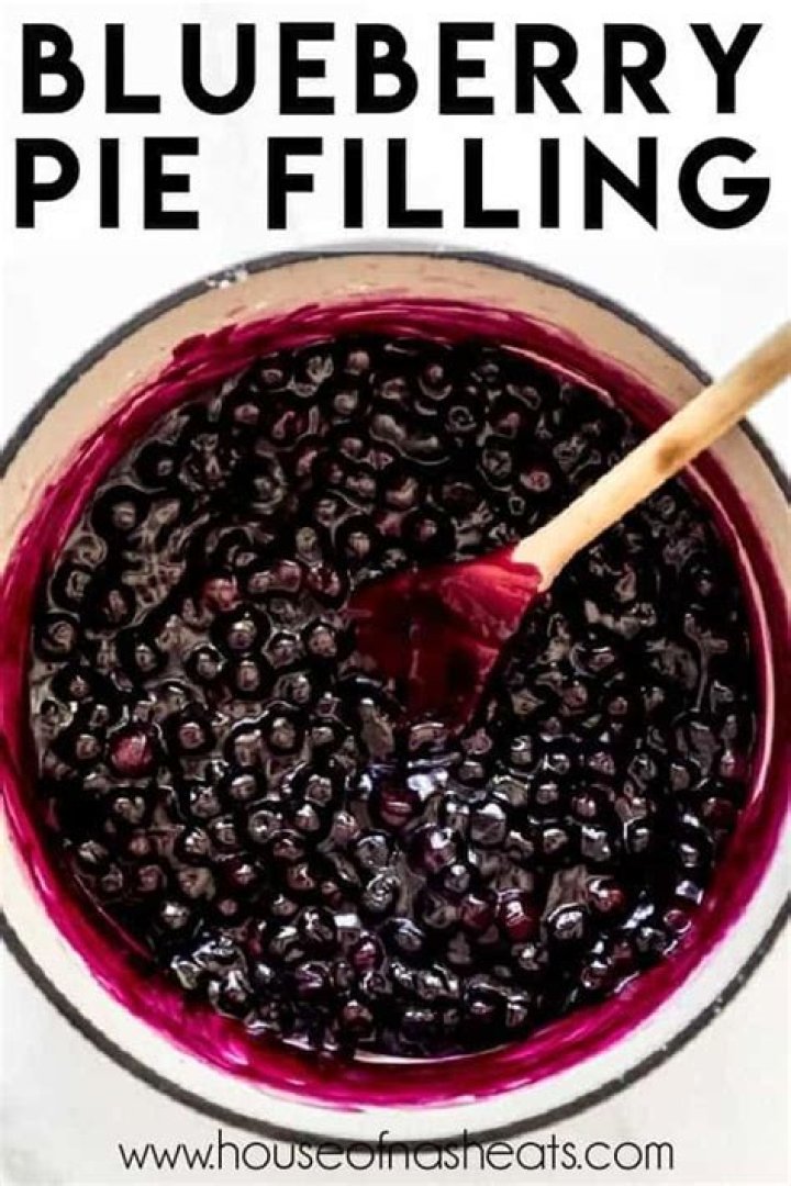 Blueberry Pie Filling in a glass jar with a gold spoon.