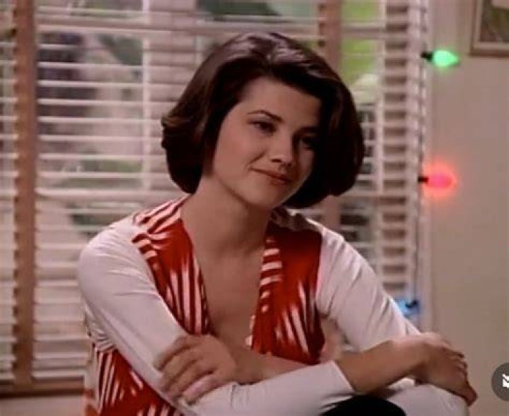 Daphne Zuniga in a red top poses for a photo.