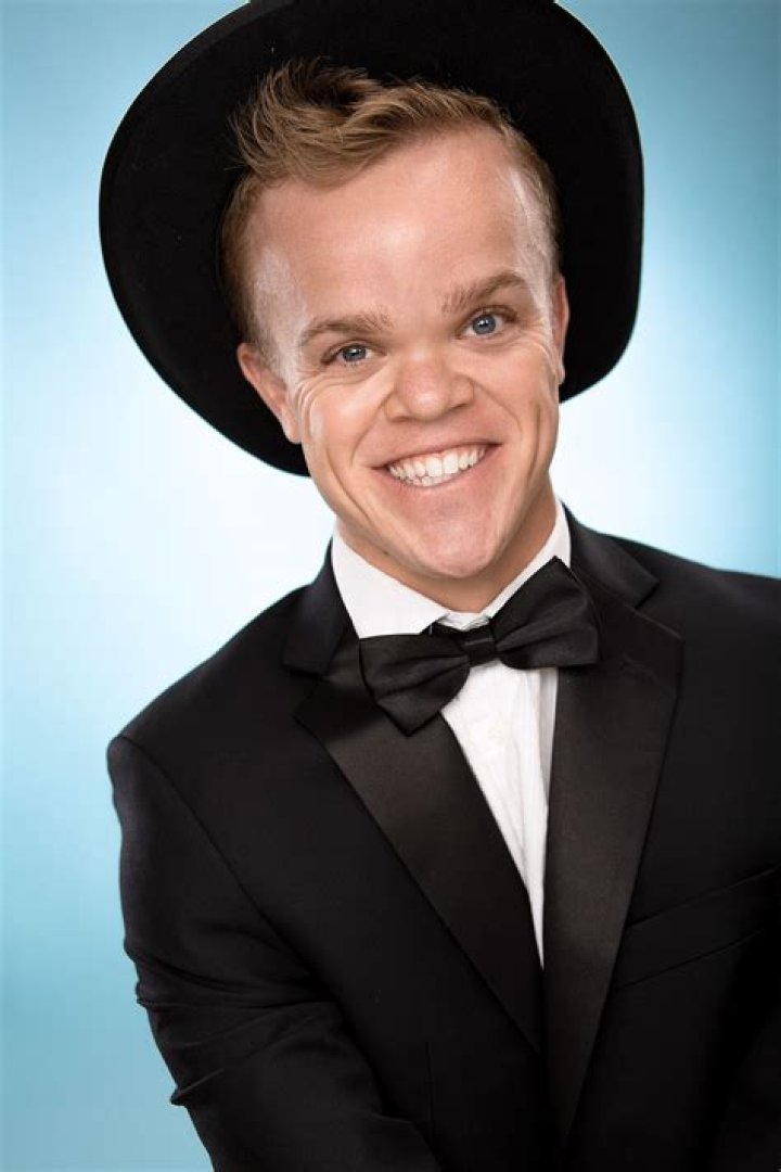 Kyle Pacek in a black suit and a black hat.