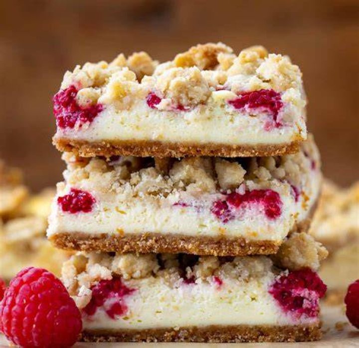 Raspberry bar on a piece of parchment paper with raspberries next to it.
