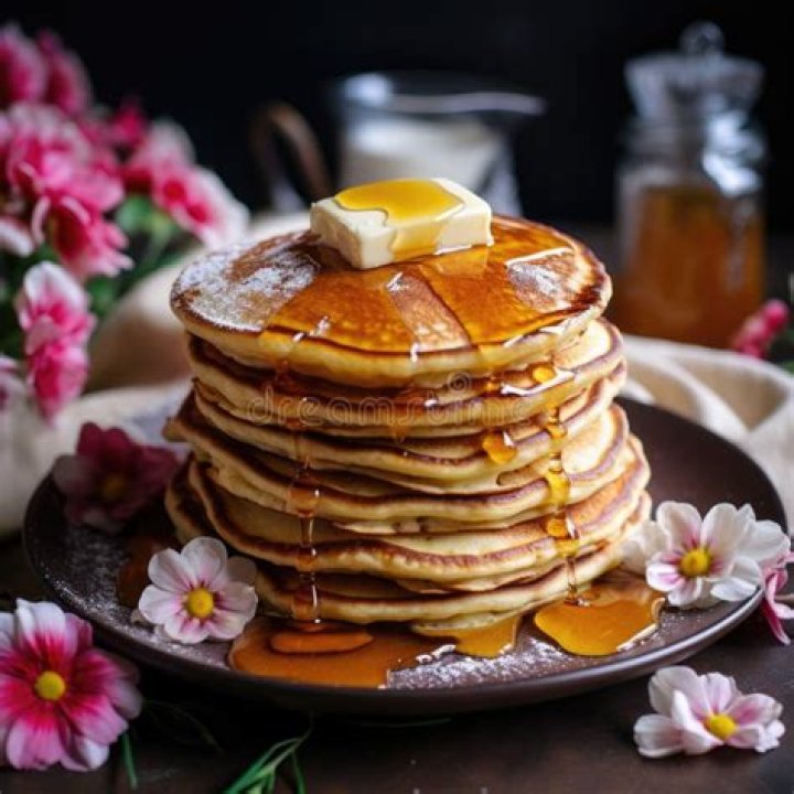 Stack of pancakes topped with banana, chocolate and nuts.