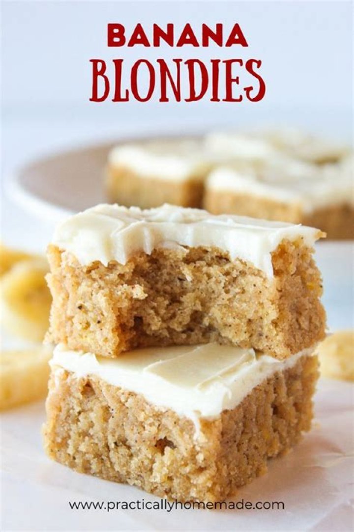 Two blondies topped with frosting and dried cranberries.
