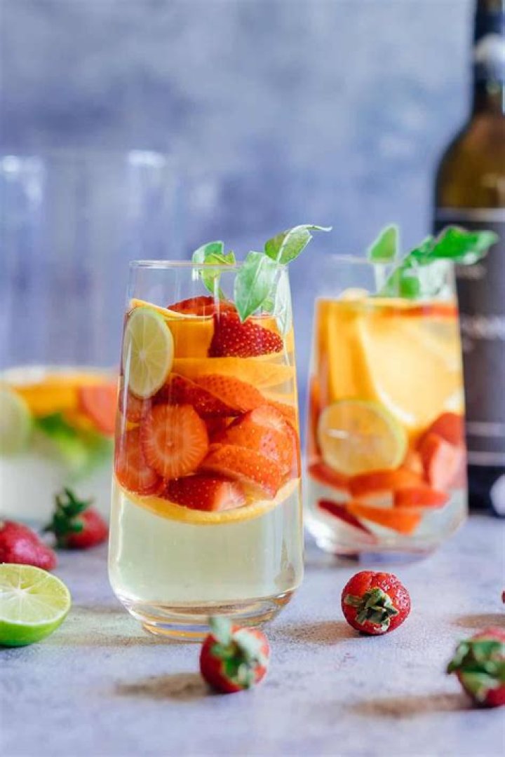 Wine, oranges, strawberries, on a board.